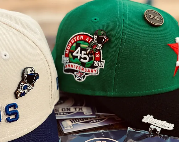 Custom astronaut enamel pins on flat-brim snapback hats.