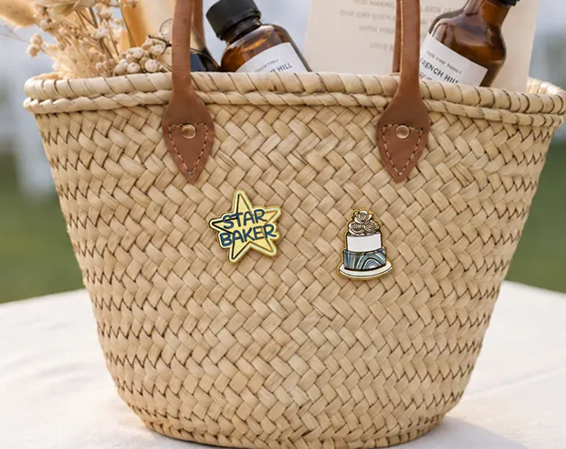 Two baking-themed pins displayed on a woven straw basket