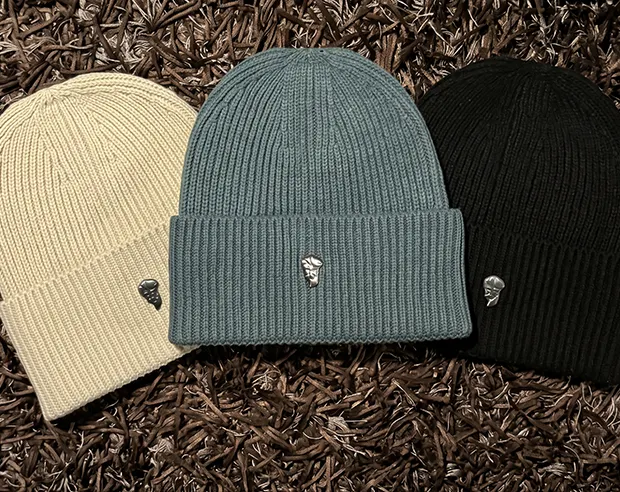 Small silver metal pins displayed on beanie hats