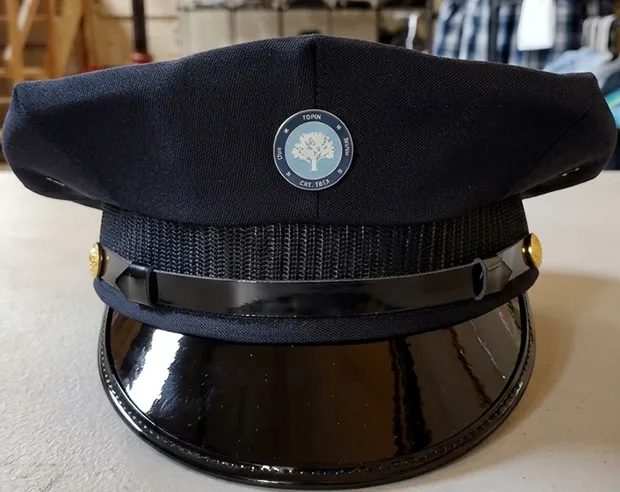A round tree logo pin on a dark blue conductor hat