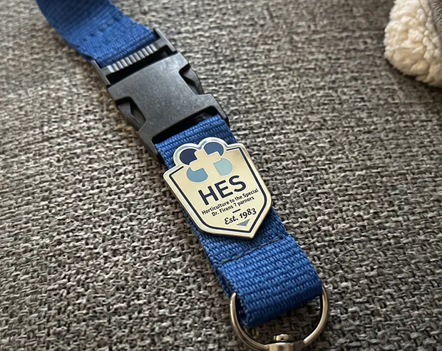 A HES printedl pin attached to a blue lanyard