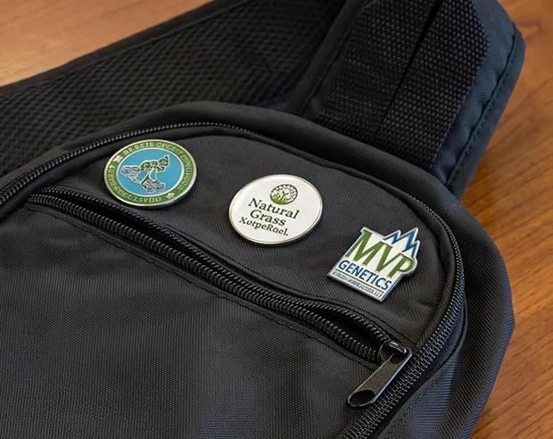 A collection of custom pins displayed on a black messenger bag