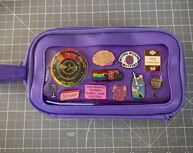 Cool custom pins displayed inside a purple pencil case pouch