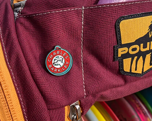 A "Charles Barkley" dog logo pin on a burgundy school bag.
