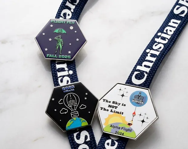Hexagonal space-themed pins displayed on a school lanyard.