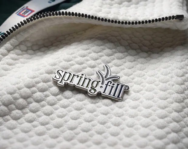 A springfill logo silver plated pin on a white fleece sportswear jacket