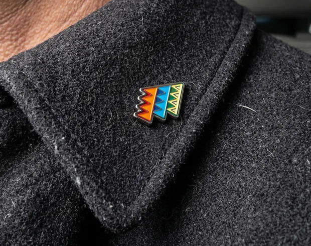 A geometric custom streetwear style enamel pin on a dark wool coat