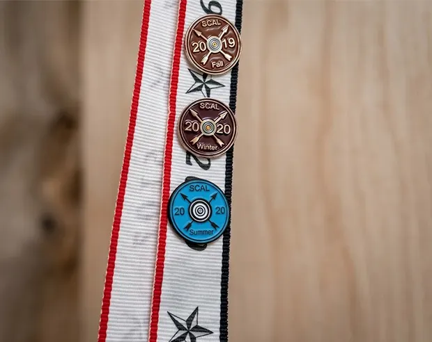 Target-themed SCAL achievement pins pinned on a striped team lanyard