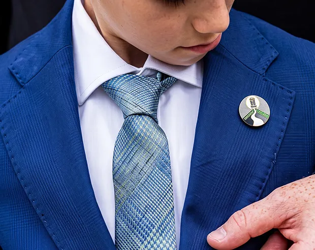 A custom round hard enamel pin on a blue uniform lapel