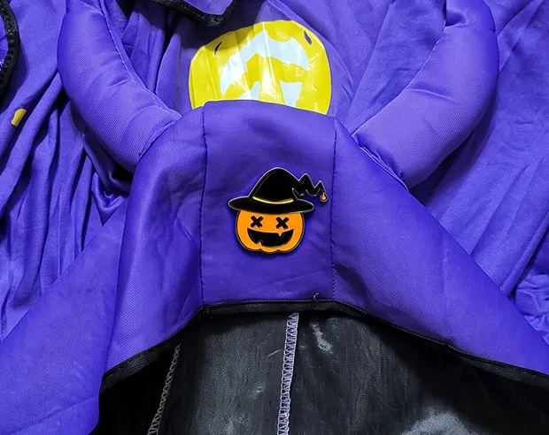 A Halloween pumpkin enamel pin pinned to a purple costume cape