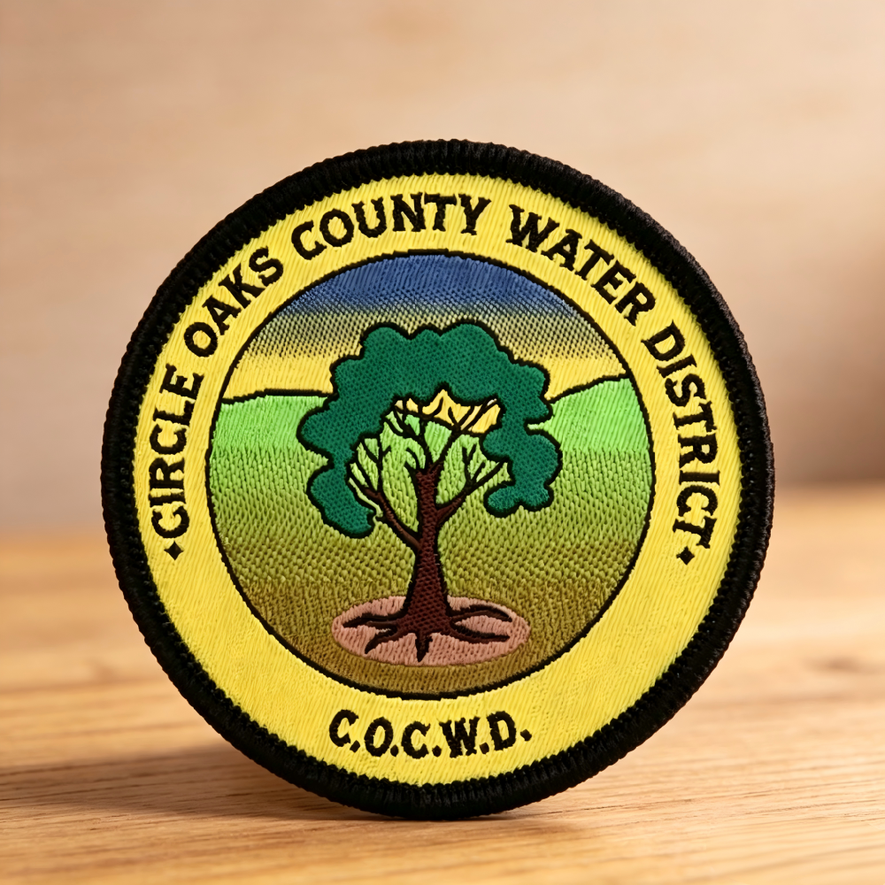 Round custom woven patch with merrowed edge featuring tree design and small letterin